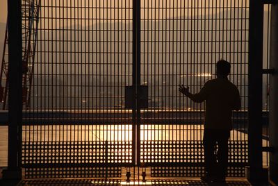 Silhouette man standing against illuminated lights at sunset