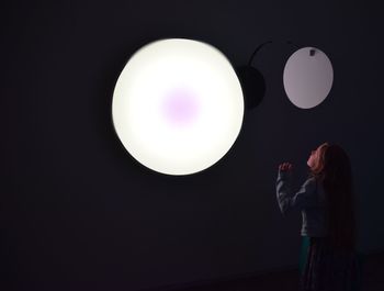 Full length of man holding balloons against black background