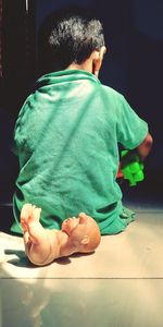 Rear view of boy sitting on floor at home