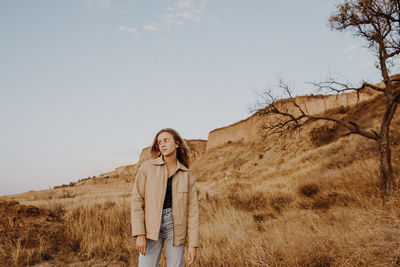 Portrait of woman standing on field against sky