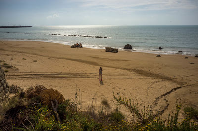 Scenic view of beach with man standing on sand against sky