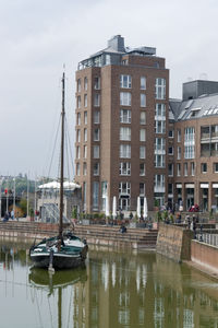 Boats moored at harbor against buildings in city