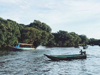 Boats sailing in river against sky