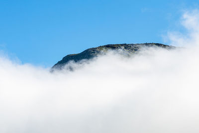 Scenic view of cloudscape covered mountain against clear sky