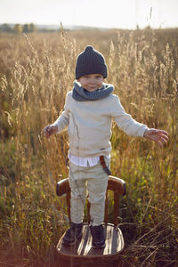 Fashionable boy child stand on a chair in autumn on the field