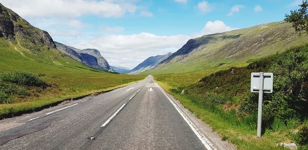 Diminishing perspective of empty road by mountains against sky