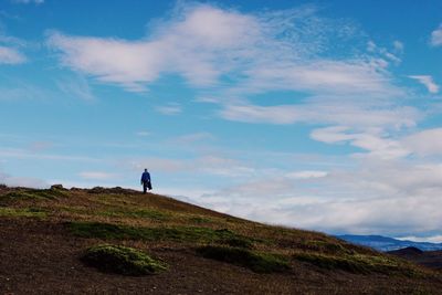 Rear view of man walking on mountain against sky