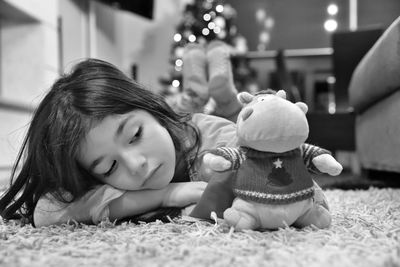 Close-up of sad girl with toy lying on carpet at home