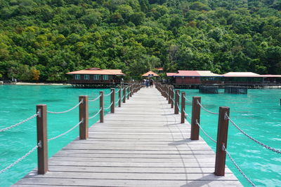 Pier over sea against trees