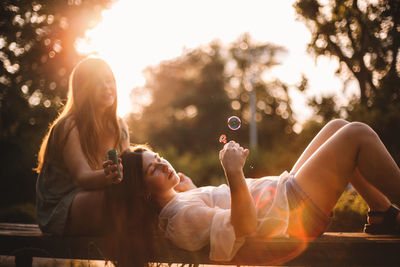 Lesbian couple playing with bubbles while relaxing in park in summer