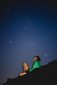 Low angle view of man sitting against night sky