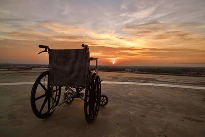 An empty wheelchair on the deck as the sun sets.