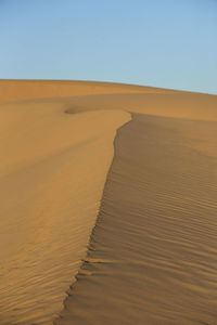 Scenic view of desert and sand dune against clear sky