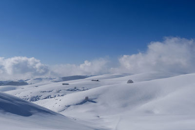 Scenic view of snowcapped mountains against blue sky