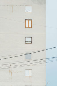 Minimalist building with different windows at every level and cables in the foreground