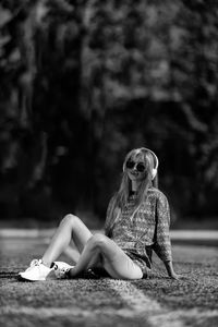 Young woman sitting on footpath