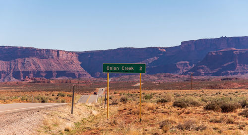 Road sign in desert against clear sky