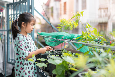 Side view of girl watering plants