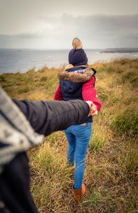 Rear view of couple on beach against sky
