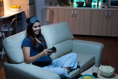 Young woman using laptop while sitting on sofa at home