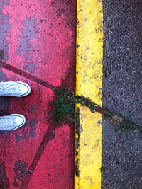 Low section of person standing on yellow road