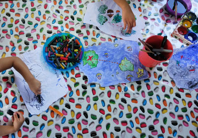 Cropped hands of children drawing on papers