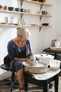 Potter making bowl on wheel. self-employed pottery artist in creative studio working raw clay person