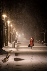 Rear view of man walking on street at night