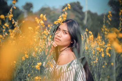 Portrait of woman by yellow flowering plants