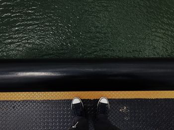 Low section of person standing boat deck over sea