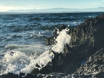 Waves splashing on shore against sky