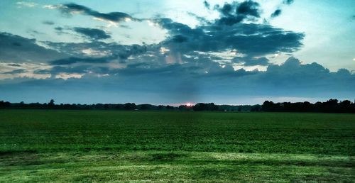 Scenic view of grassy field against cloudy sky