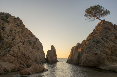 Rock formations by sea against clear sky