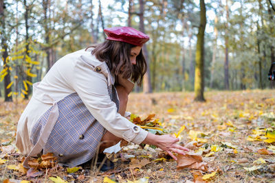 Side view of young woman sitting in forest