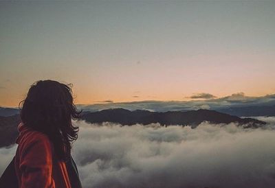 Rear view of woman looking at mountains during sunset