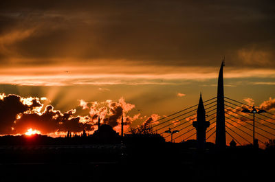 Low angle view of silhouette trees against cloudy sky