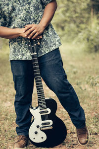 Low section of man holding guitar
