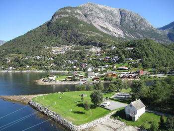 Scenic view of lake by buildings and mountains against sky