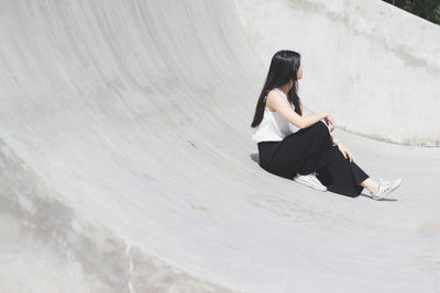 Young woman sitting on concrete