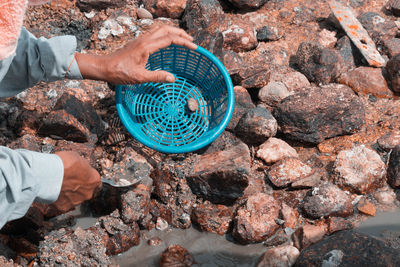 Cropped image of worker with basket on stones