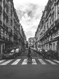 Vehicles on road against sky in city