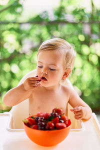 Baby girl sitting while eating strawberry