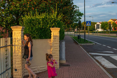 Side view of mother with daughter standing against plants