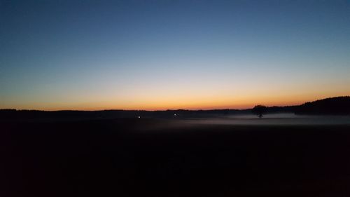 Scenic view of beach against clear sky at sunset