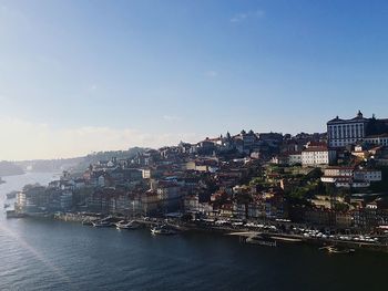 Cityscape by sea against clear sky