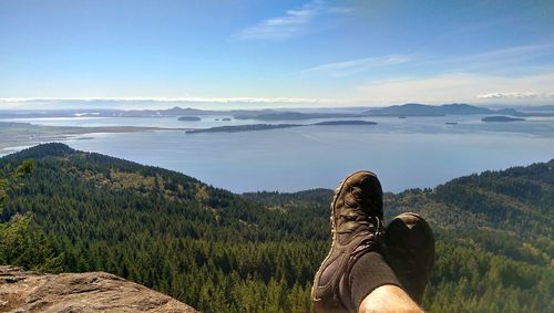 Low section of man sitting on landscape against sky