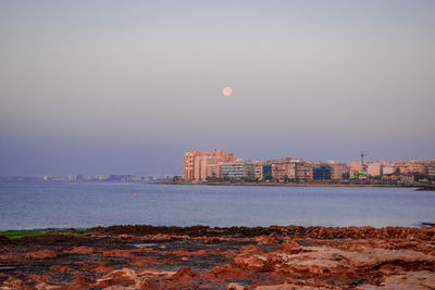 Moon setting over a town and a bay