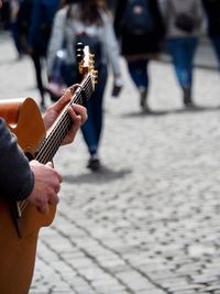 Cropped image of man playing guitar on street