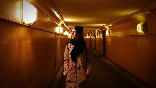 Woman standing in illuminated underground walkway