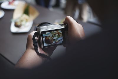 Midsection of person photographing with mobile phone